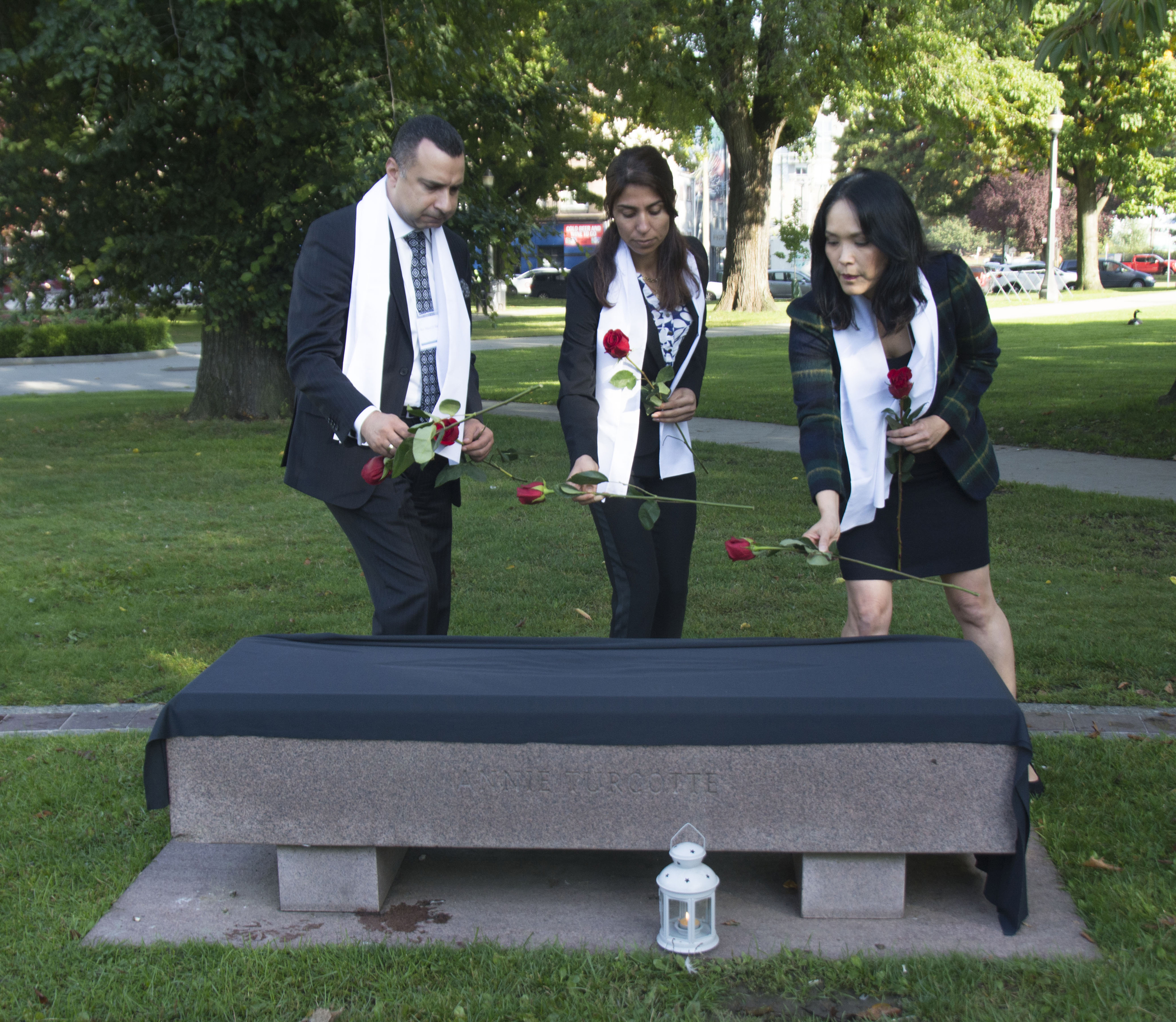 Placing roses on the veiled bench for Yazidi people who died in the genocide, starting August 3, 2014.Majed El Shafie of One Free World International with Adiba and MP Jenny Kwan (Vancouver East)